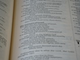 A close-up view of the pages of a book, featuring printed text in English. The text is organized into paragraphs with distinct headings, and the layout resembles that of a religious or reference book. The pages are a light cream color with dark, clear typography.