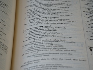 A close-up view of the pages of a book, featuring printed text in English. The text is organized into paragraphs with distinct headings, and the layout resembles that of a religious or reference book. The pages are a light cream color with dark, clear typography.