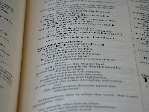 A close-up view of the pages of a book, featuring printed text in English. The text is organized into paragraphs with distinct headings, and the layout resembles that of a religious or reference book. The pages are a light cream color with dark, clear typography.