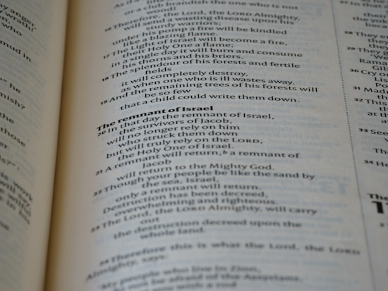 A close-up view of the pages of a book, featuring printed text in English. The text is organized into paragraphs with distinct headings, and the layout resembles that of a religious or reference book. The pages are a light cream color with dark, clear typography.
