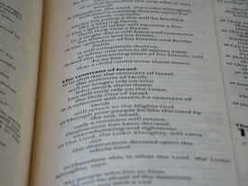 A close-up view of the pages of a book, featuring printed text in English. The text is organized into paragraphs with distinct headings, and the layout resembles that of a religious or reference book. The pages are a light cream color with dark, clear typography.