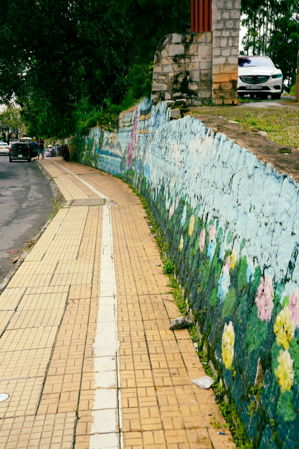 a wall with flowers painted on it next to a street