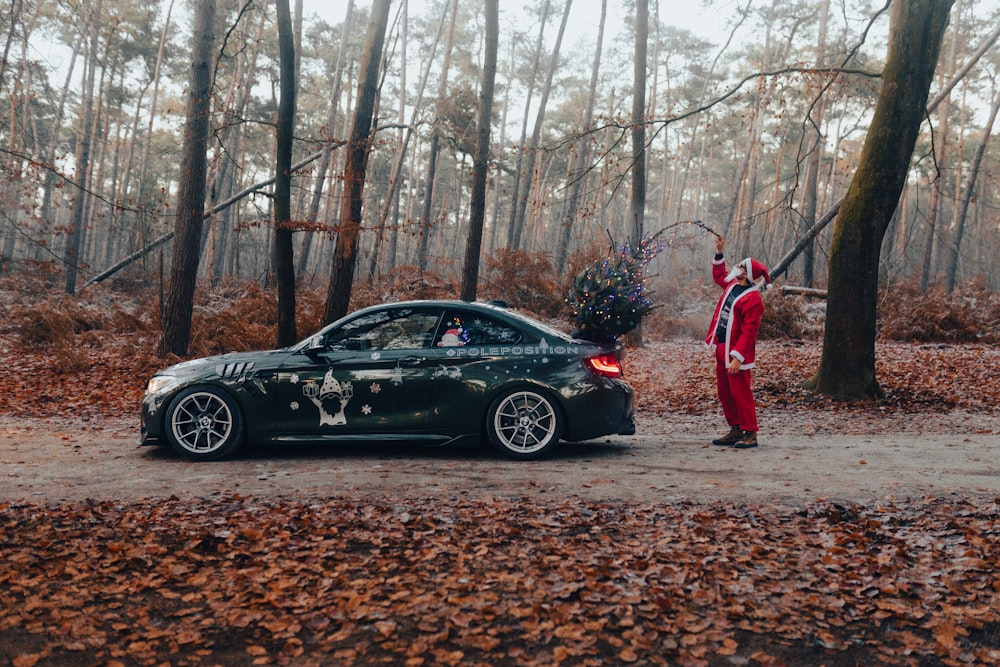 a man in red jumpsuit standing next to a green car