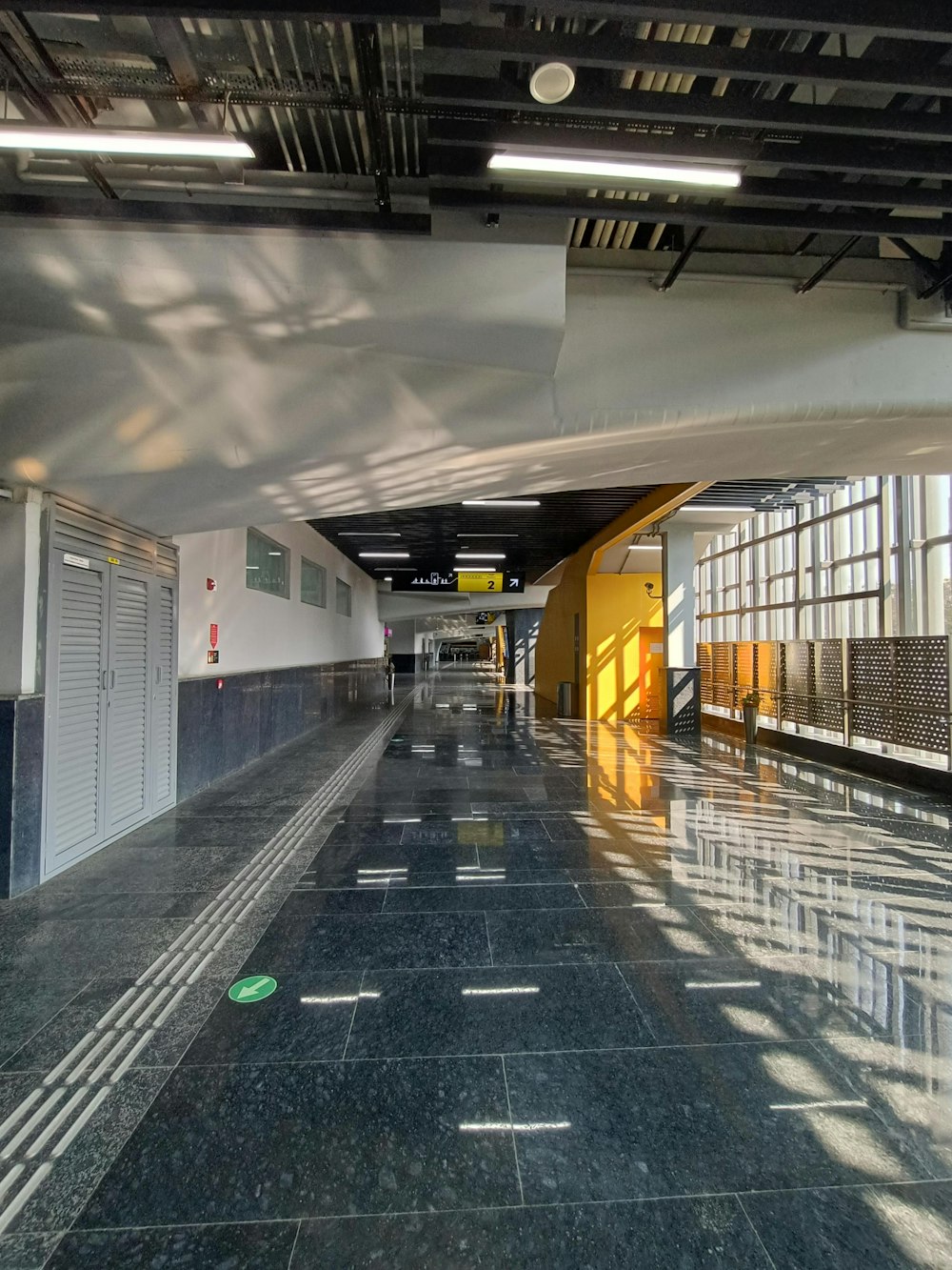 a long hallway with black marble floors and yellow doors