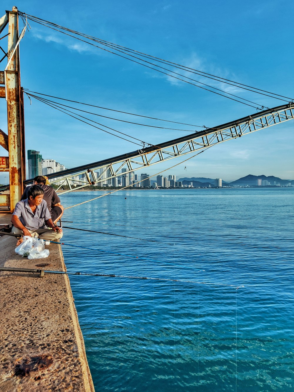 a man sitting on a dock next to a body of water