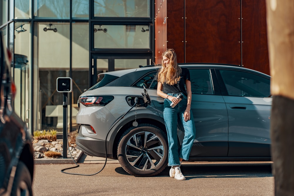 a woman standing next to a blue car