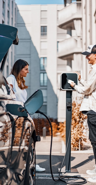 a man and a woman are charging their cars