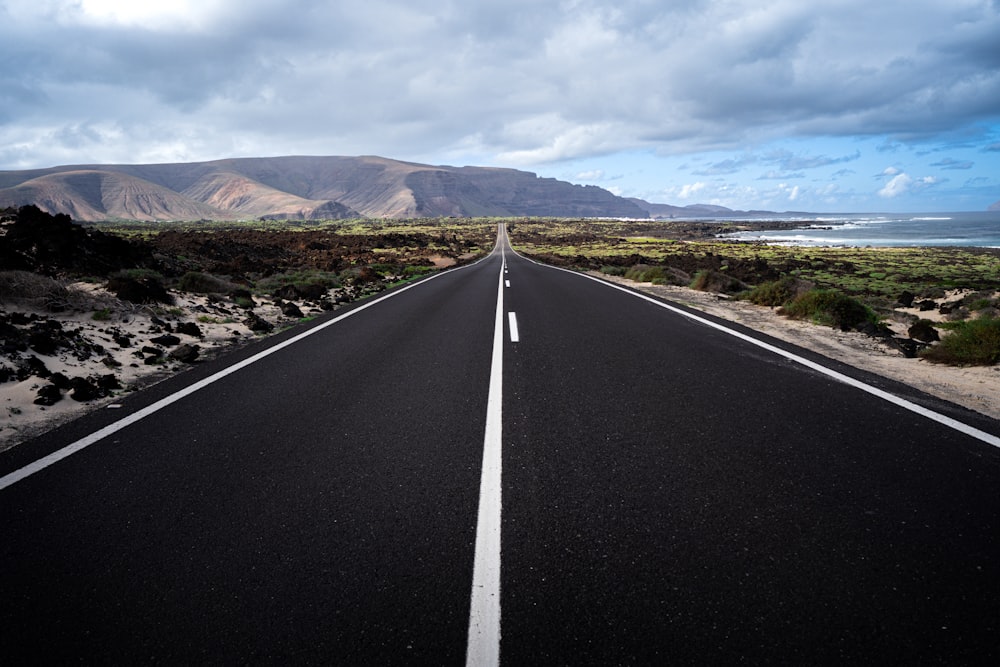 an empty road with a mountain in the background