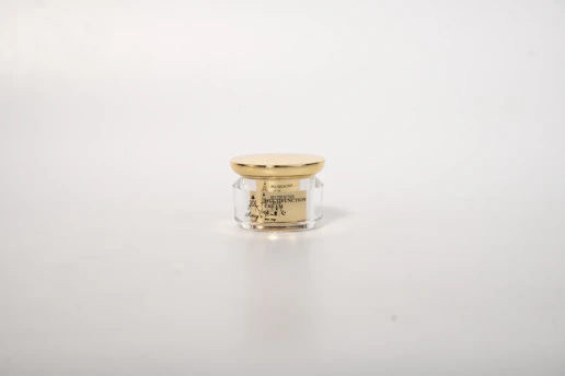 Elegant jar of luxury anti-aging cream with soft gold accents on a white marble surface.