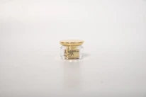 Elegant glass jar of cream with subtle gold accents resting on a marble countertop