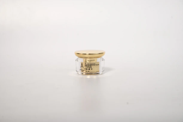 Elegant jar of Gold Fairness Kandhi Lepam cream placed on a marble surface with gold accents.