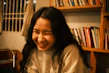 Smiling woman holding a book in a cozy home setting.