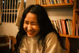 Portrait of a smiling author holding a freshly printed novel in a cozy library setting.