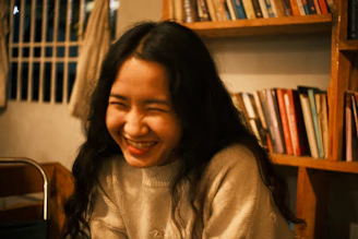 An author holding their first published book with a joyful smile in a warmly lit study.