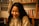 A smiling woman reading a book in a cozy setting.