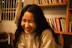 A joyful woman smiling while reading a blog on her laptop in a cozy living room.