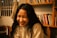 A woman smiling while reading a book in a cozy living room.