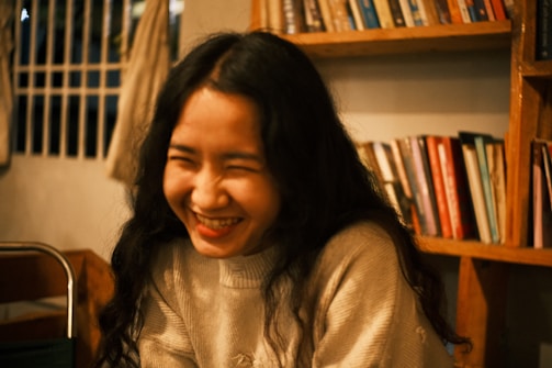 A warm portrait of Edith Aguiar smiling confidently in a cozy office setting filled with books and plants.