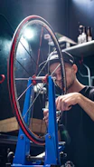 A mechanic adjusting alignment tools on a semi-truck's front axle in a workshop.