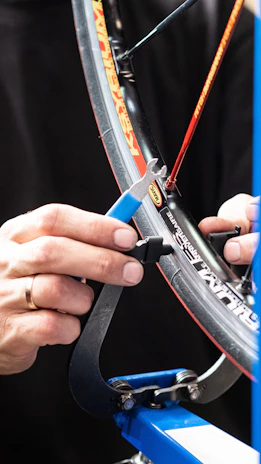 Close-up of a bicycle mechanic's hands adjusting gears with precision tools.