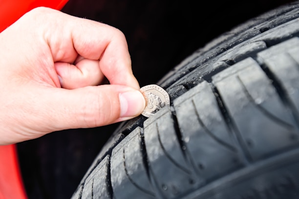A professional driver checking the car's tires before a trip on a sunny day.