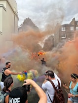 A warm, inviting photo of a couple smiling with colorful smoke gently swirling around them at an outdoor event.