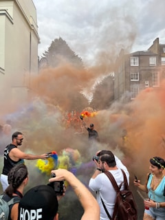 A warm, inviting photo of a couple smiling with colorful smoke gently swirling around them at an outdoor event.