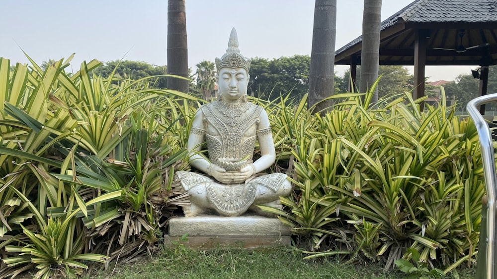 a statue of a buddha sitting in the middle of a garden