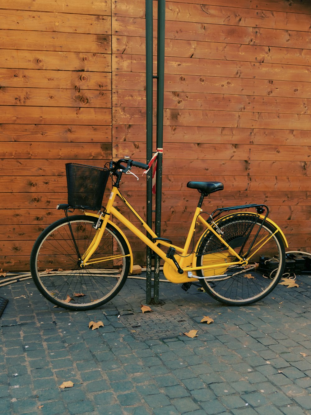 a yellow bicycle parked next to a wooden fence
