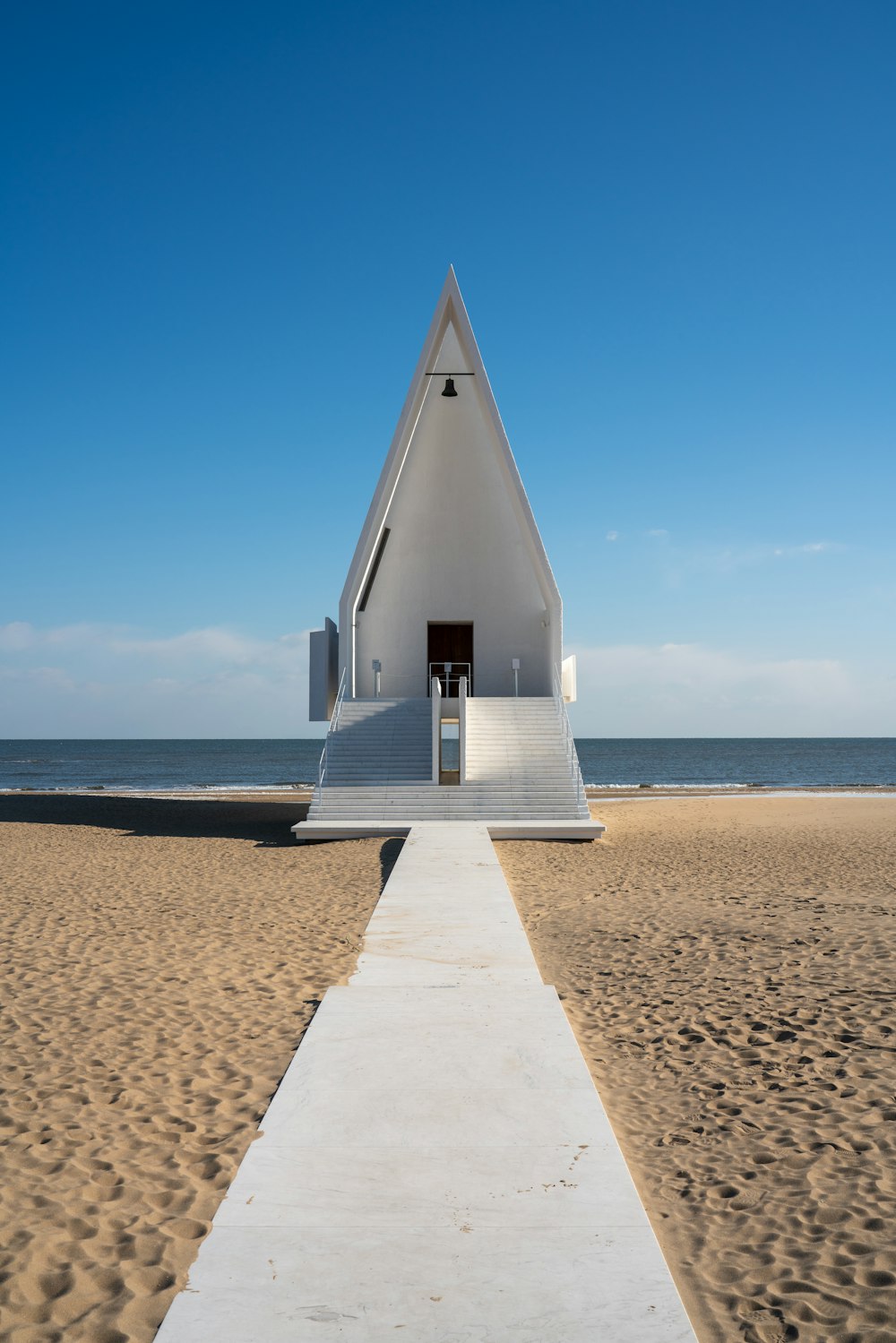 a walkway leading to a white building on the beach