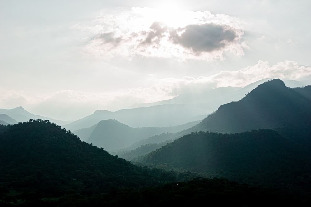 the sun shines through the clouds over the mountains