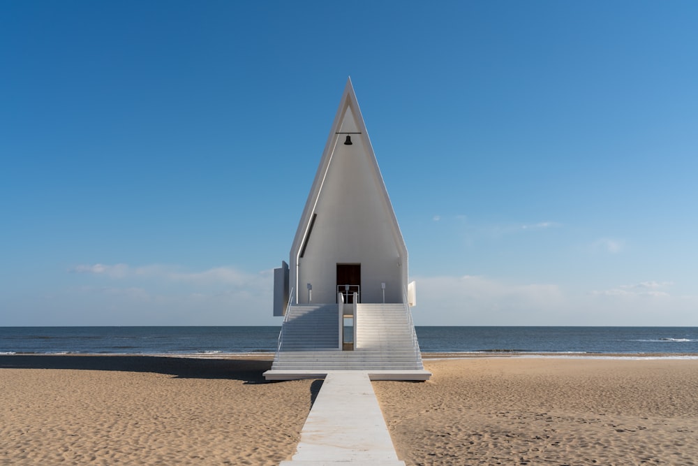 a white building on the beach with stairs leading to it