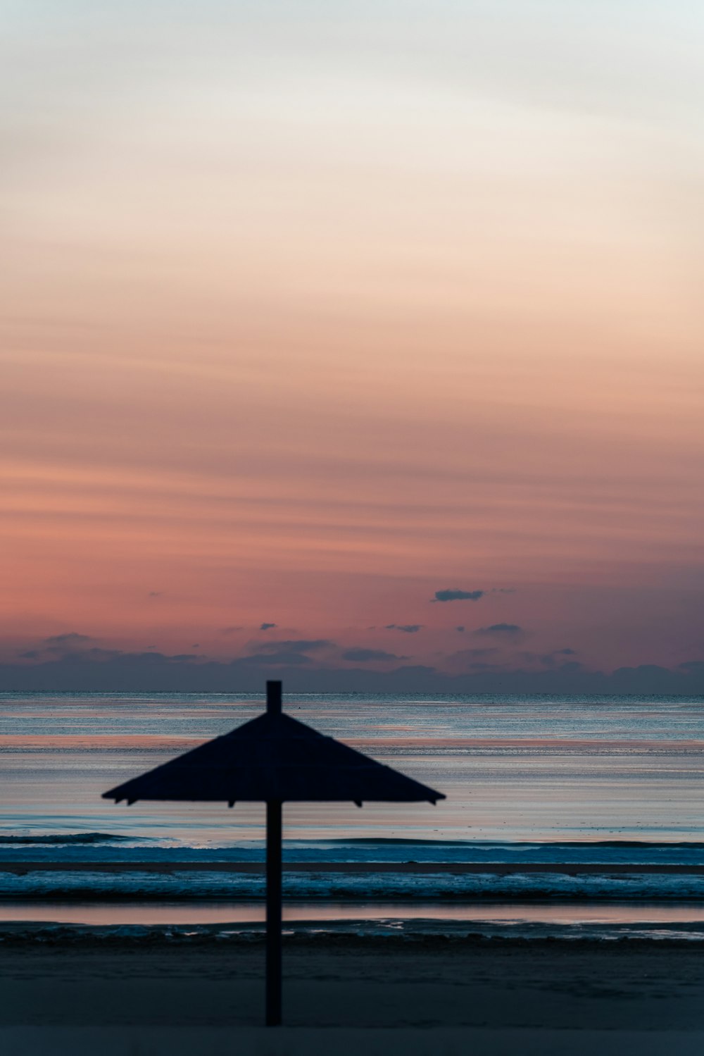 a beach umbrella sitting on top of a sandy beach