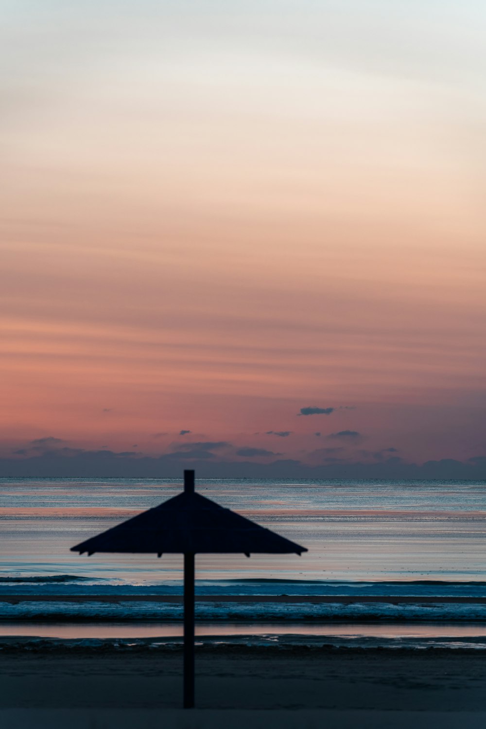 un parasol assis au sommet d’une plage de sable