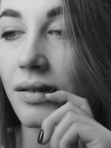 A serene black-and-white portrait of a woman lost in thought, highlighting intimate emotion.