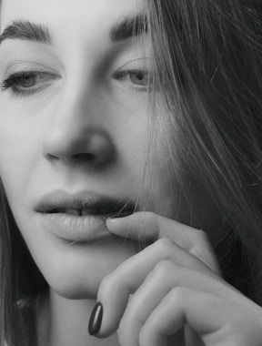 A serene black-and-white portrait of a woman lost in thought, highlighting intimate emotion.