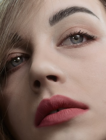 Elegant close-up of a woman with perfectly shaped natural eyebrows and subtle lip color in soft lighting.