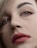 A close-up of a person's face focusing on well-defined eyebrows, expressive eyes with subtle makeup, and full lips adorned with a matte pink lipstick. The image captures fine details of the skin texture and hair strands.