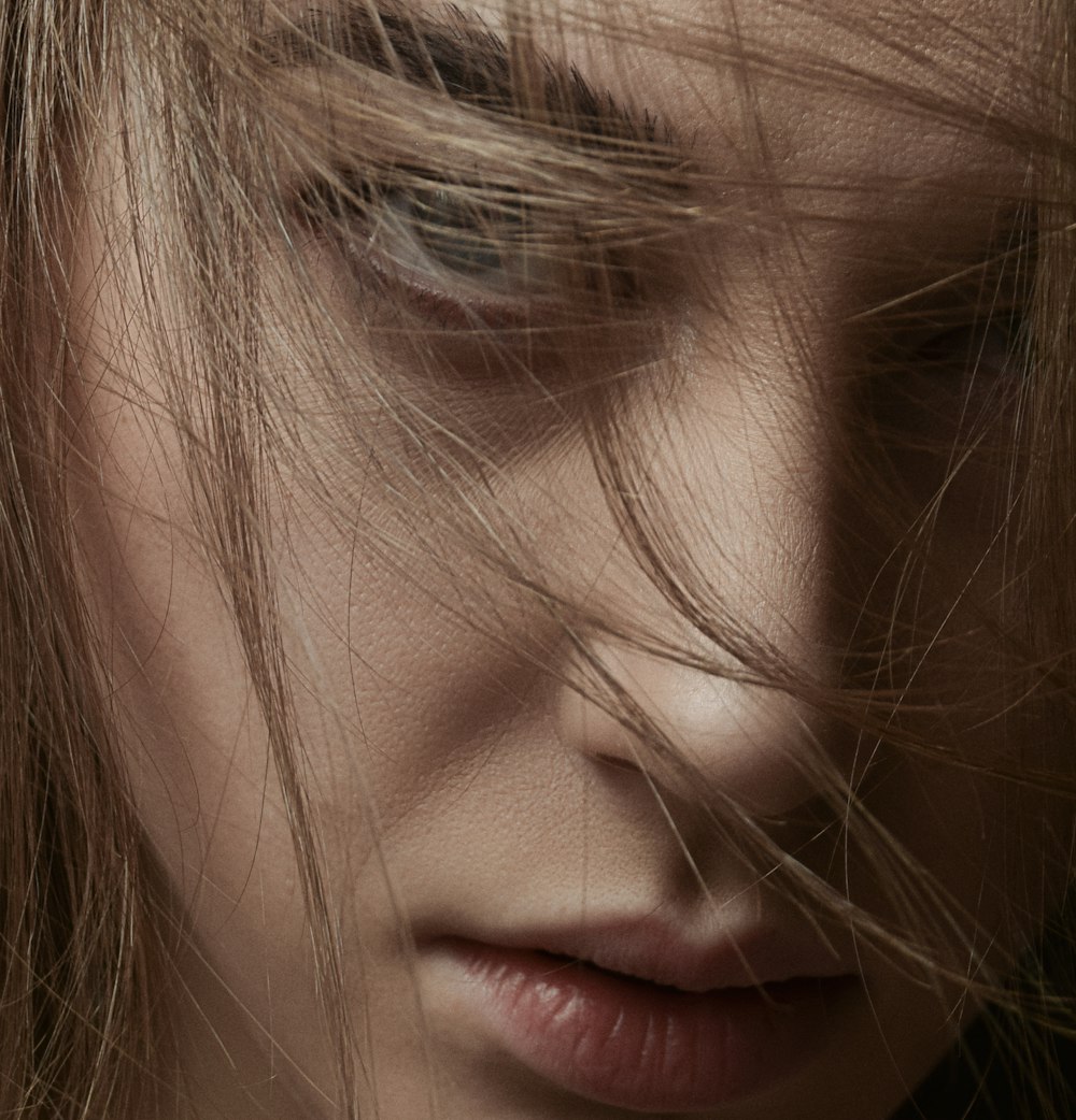 a close up of a woman's face with hair blowing in the wind