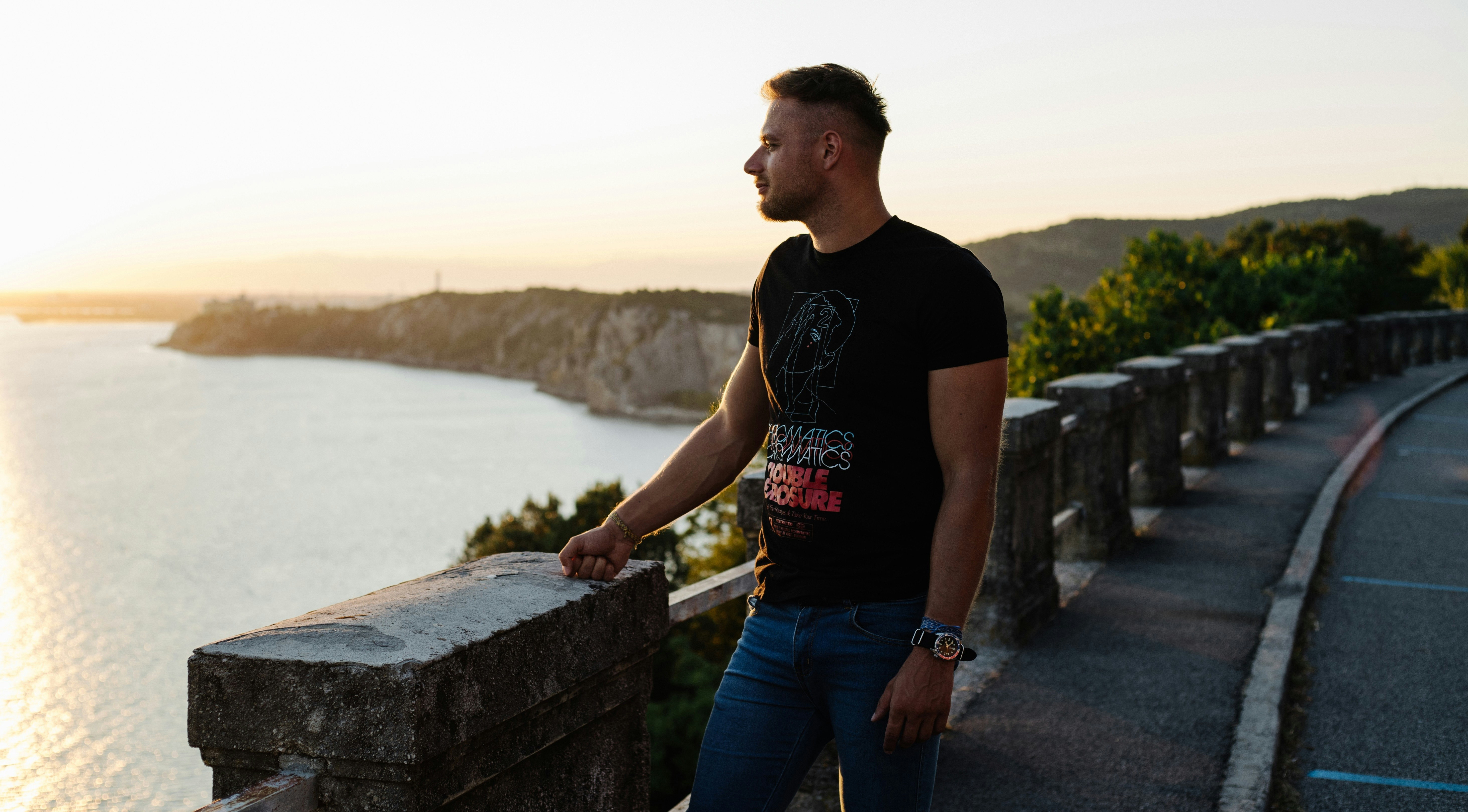 A man standing next to a railing overlooking a body of water photo ...