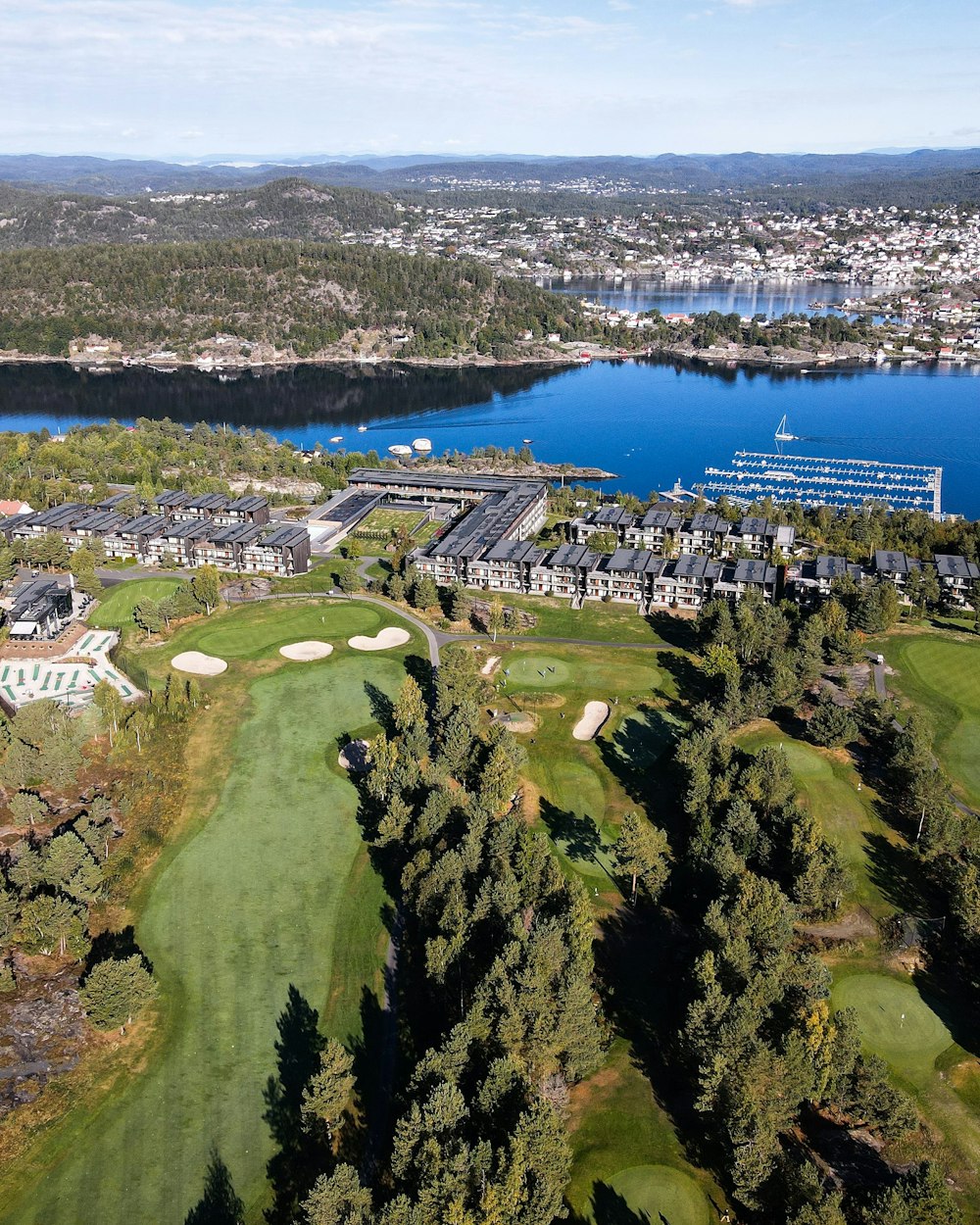 an aerial view of a golf course with a lake in the background