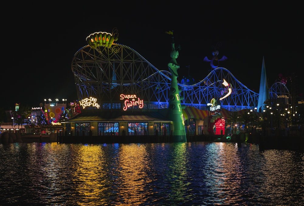 an amusement park lit up at night with a ferris wheel in the background