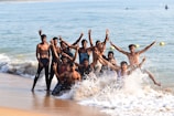 A group of friends laughing on a sunny beach wearing colorful madeyalook.apparel swim briefs.