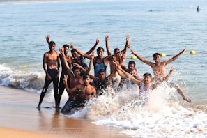 A joyful group of friends wearing ebony waves swimwear laughing and splashing in the ocean