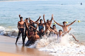 A joyful group of friends wearing ebony waves swimwear laughing and splashing in the ocean
