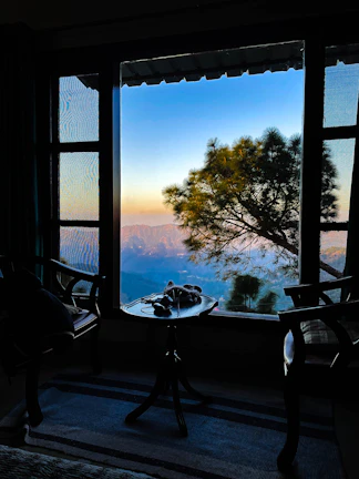 A serene mountain landscape view from the hotel’s large panoramic window at sunset.