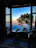 Cozy hotel room with a large window overlooking a serene mountain landscape at sunset.