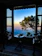Cozy hotel room with a large window overlooking a serene mountain landscape at sunset.