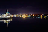 A serene night view of the illuminated mosque with a family silhouette.