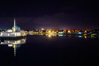 A peaceful night sky above a mosque illuminated by soft lights.